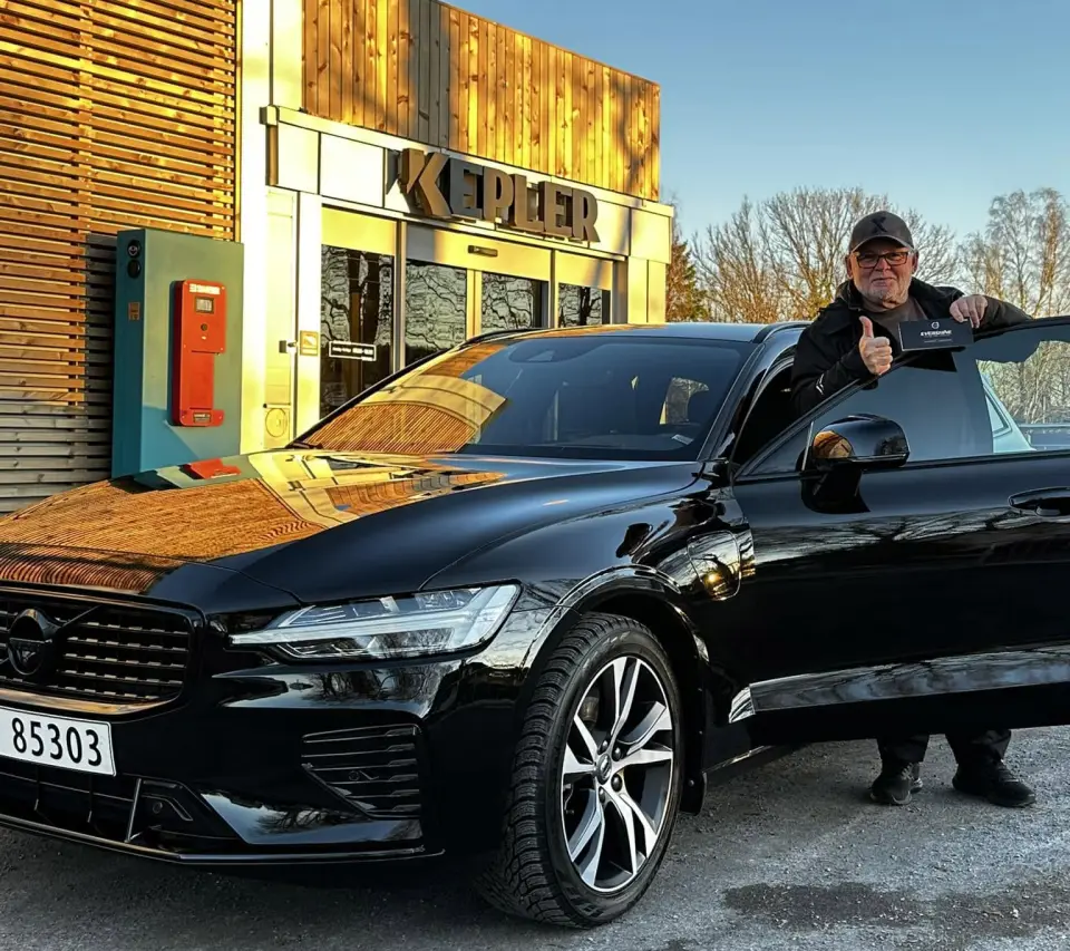 Fornøyd kunde med Evershine-sertifikatet foran sin svarte Volvo utenfor Kepler Bilservice